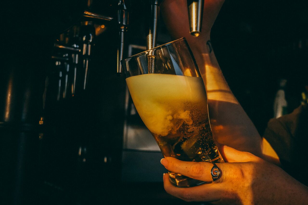 Bière blonde versée au robinet, lumière rasante de fin de journée.