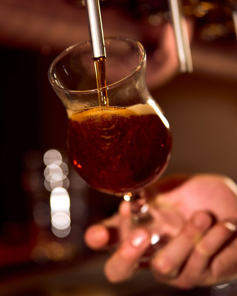 Bière ambrée versée au robinet dans un verre tulipe.